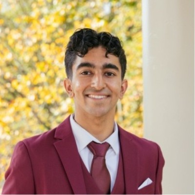 Yash Gandhi smiling in a burgundy suit